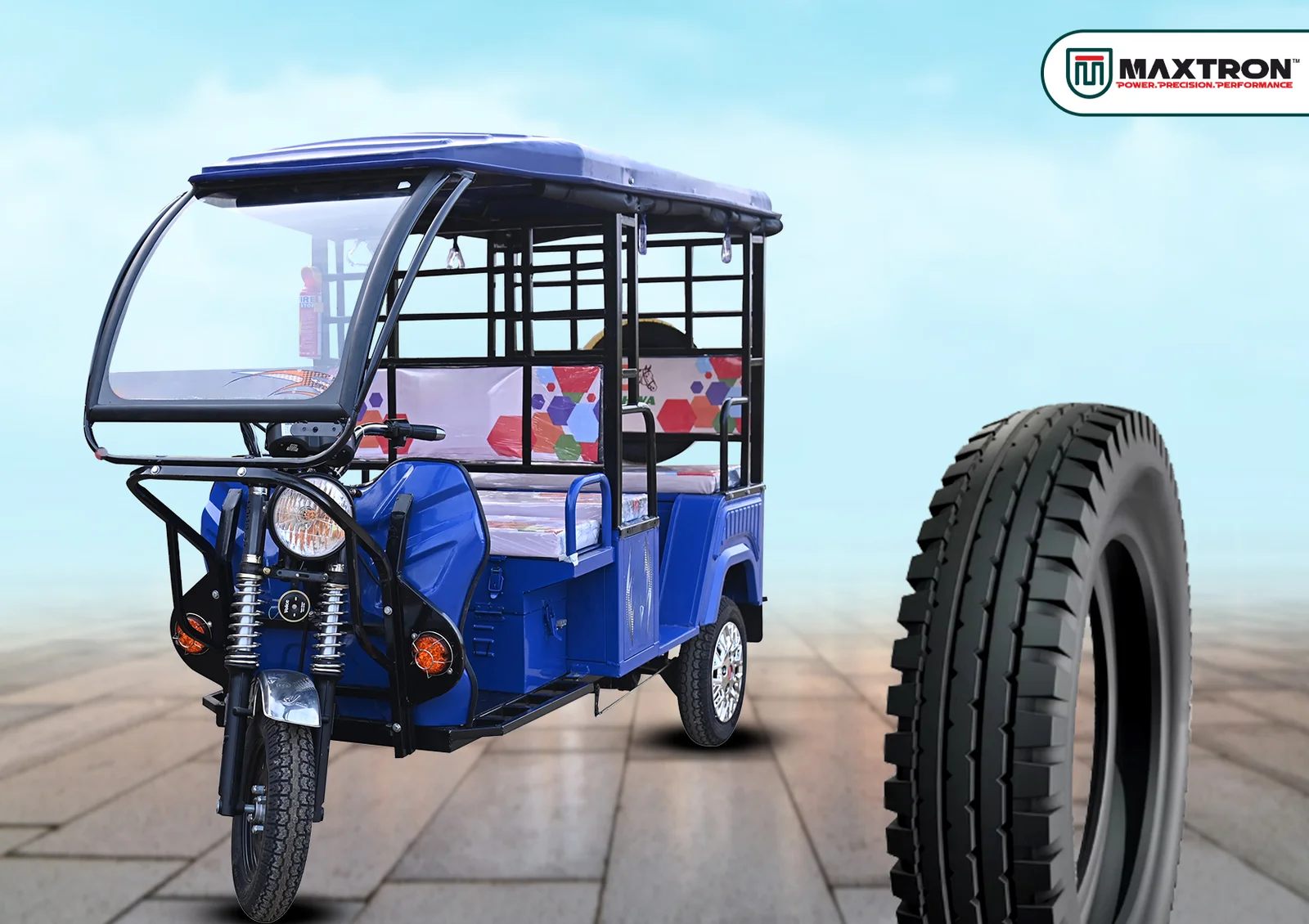 Blue electric passenger rickshaw alongside a heavy-duty three-wheeler tyre designed for superior load capacity, durability, traction, and reliable urban transportation.
