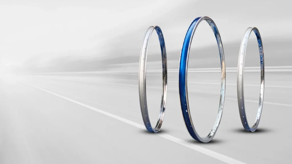 Premium bicycle rims in steel and alloy finishes displayed on a road background, showcasing durability, strength, precision engineering, and reliable cycling performance.