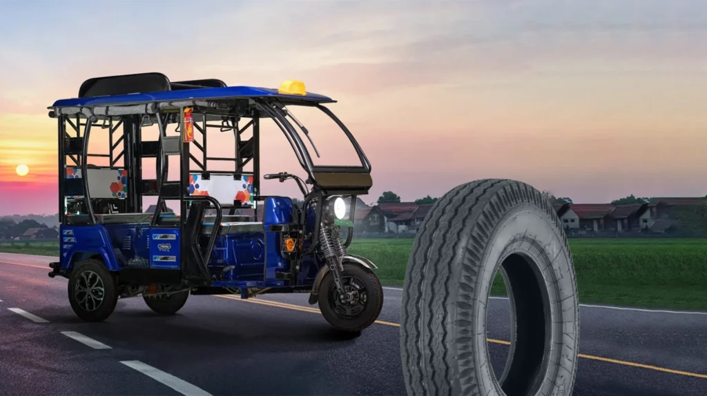 Blue electric rickshaw displayed with a premium three wheeler tyre, showcasing durable tread design, high load capacity, stability, and reliable commercial road performance.