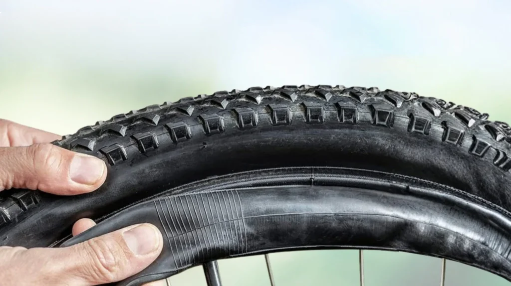 Close-up of a bicycle tyre and inner tube during installation, showcasing a durable bicycle inner tube designed for excellent air retention, puncture resistance, and reliable cycling performance.